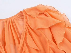 Close-up of orange ruffled shirt fabric showing delicate layered chiffon texture