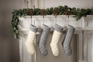 Detail of four knitted Christmas stockings in white and grey with fish scale patterns
