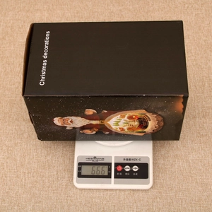 Detailed view of musical Christmas gift box being weighed, showing 666g on a digital scale