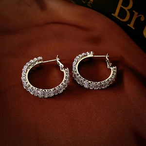 Détail de boucles d'oreilles créoles serties de zircons baguettes sur soie rouge