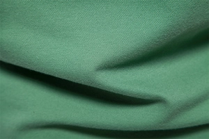 Close-up of green pique knit fabric texture showing high-quality breathable cotton mesh