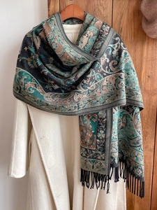Ethnic paisley scarf with black tassels styled on a white coat and wooden door background