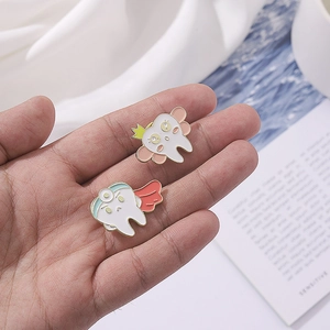 Cartoon tooth enamel pin set featuring a crowned tooth with wings and a superhero tooth badge