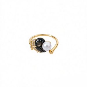 Vintage gold-plated ring with white pearl and black diamond-studded leaf on white background