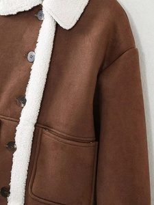 Detail of brown faux suede jacket featuring white sherpa lining and patch pockets
