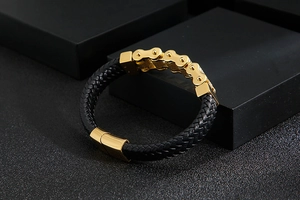 Detail of black braided leather bracelet with golden bike chain link and magnetic clasp
