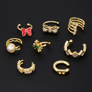 8-piece gold ear cuff set with zircon bow and pearl accents on black background