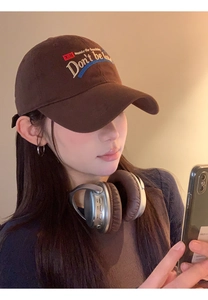 Brown baseball cap with colorful letter embroidery shown with over-ear headphones