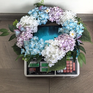 Weight measurement of a blue and purple hydrangea wreath with butterflies on a digital scale