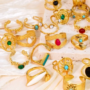 Vintage 14k gold plated stainless steel rings with colorful gemstones on a stone surface
