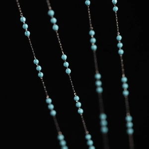 Macro shot of turquoise beaded tassels and silver chain detail on the necklace