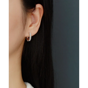 Close-up of model wearing silver hoop earrings with small pearls and crystals