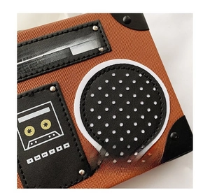 Close-up of vintage radio-shaped crossbody bag with lychee texture leather and rivets