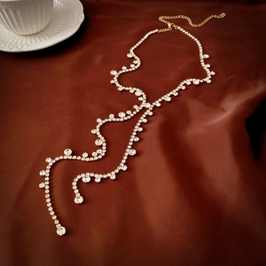 Macro detail of long tassel Y-necklace with sparkling rhinestones on luxury silk background