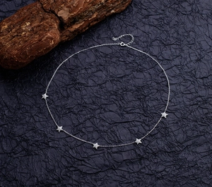 Detail of S925 sterling silver star necklace with five sparkling crystals on dark wood