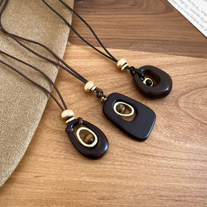 Detailed view of resin tiger eye oval pendants on minimalist brown cords and gold beads
