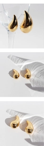 Macro shot of mirror-polished golden waterdrop earrings with elegant light reflections