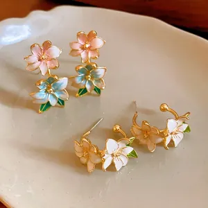 Elegant oil painting style flower earrings with gold edges and colorful petals on a ceramic tray