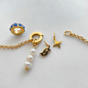 Detail of DIY bracelet charms featuring pearls, a golden star, and blue rhinestones