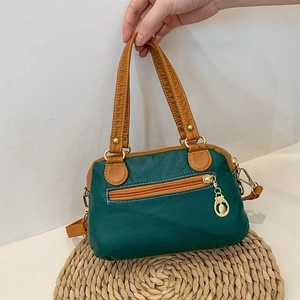 Dark green and brown dual-tone faux leather crossbody handbag on a straw mat background