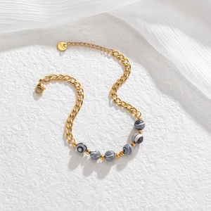 Detailed view of titanium steel gold chain with striped beads and S.Steel tag