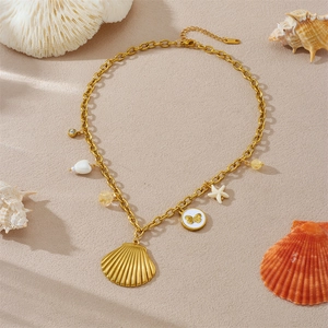 Goldene Halskette mit Muschel- und Seesternanhängern auf sandigem Hintergrund