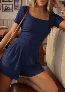 Detail of navy ribbed knit jumpsuit on a model in a cozy vintage restaurant setting