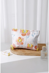 Close-up of floral embroidered cosmetic bag with orange tassels and brand label detail