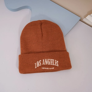 Détail du bonnet en tricot rouge rouille avec broderie blanche LOS ANGELES et texture