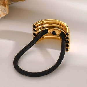 Detail of high-elastic black hair tie with polished gold multi-tube metal accessory