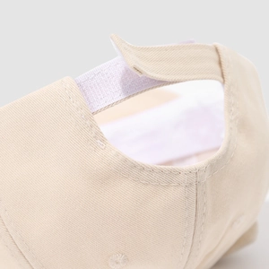 Detalle de gorra beige para bebé con cierre de velcro ajustable y tejido de algodón