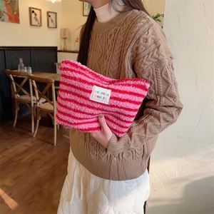 Close-up of pink and red striped plush cosmetic bag with colorful brand label details