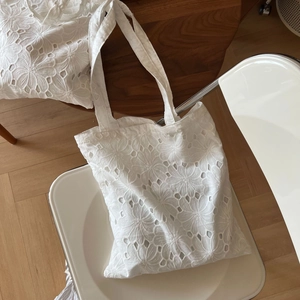 Close-up of white cotton tote bag with intricate eyelet flower embroidery and cutouts