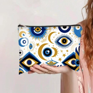 Detalle del neceser de lona con estampado de ojo turco sostenido por la mano de una modelo