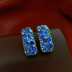 Vue macro des boucles d'oreilles rectangulaires en cristal bleu et support doré