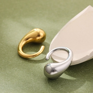 Macro shot of liquid teardrop ear cuffs in polished gold and silver metallic finishes