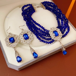 Macro shot of multi-layer blue beaded necklace and teardrop earrings in a velvet box