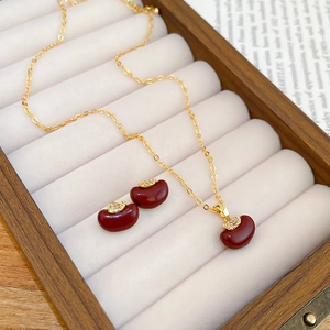 Macro detail of red apple jewelry set with gold necklace and earrings in a wooden gift box