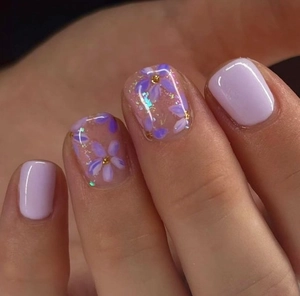 Macro detail of lavender press-on nails featuring hand-painted floral patterns and sequins