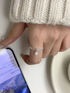 Detail of s925 silver hollow heart ring featuring a dangling white freshwater pearl charm