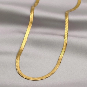 Collana a catena piatta placcata oro 18 carati su sfondo di seta grigia pregiata