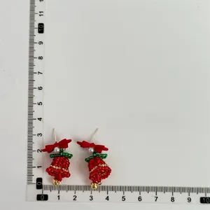 Detail shot of beaded Christmas tree earrings with size dimensions and red bow accent