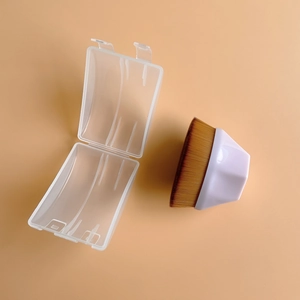 Flat lay of foundation makeup brush with white handle and brown bristles in a clear case