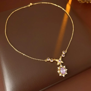 Detailed macro of a vintage gold necklace featuring purple stones and zircon accents