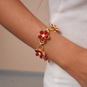 Detail shot of vintage gold chain bracelet with red glass flower charms and diamonds