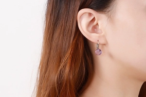 Close-up of purple round faceted crystal earring on silver hook shown on a model