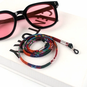Detail of colorful bohemian braided eyewear strap on white book with sunglasses