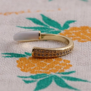 Macro shot of adjustable gold ring featuring white enamel bar and pave-set zircons