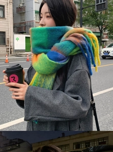 Street style view of thick mohair rainbow striped scarf with tassels on dark grey coat