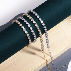 Detail of heart-shaped zircon tennis bracelets in gold and silver on a green silk roll